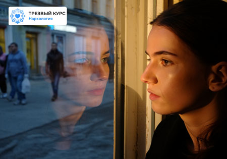 Девушка стоит у окна, смотрит на прохожих